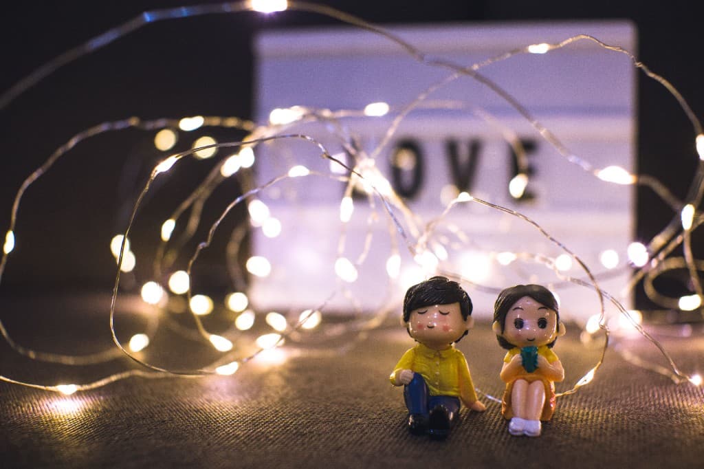 A cozy couple figurine scene lit by warm fairy lights